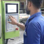 A factory worker in Karachi uses a control panel of an industrial machine.